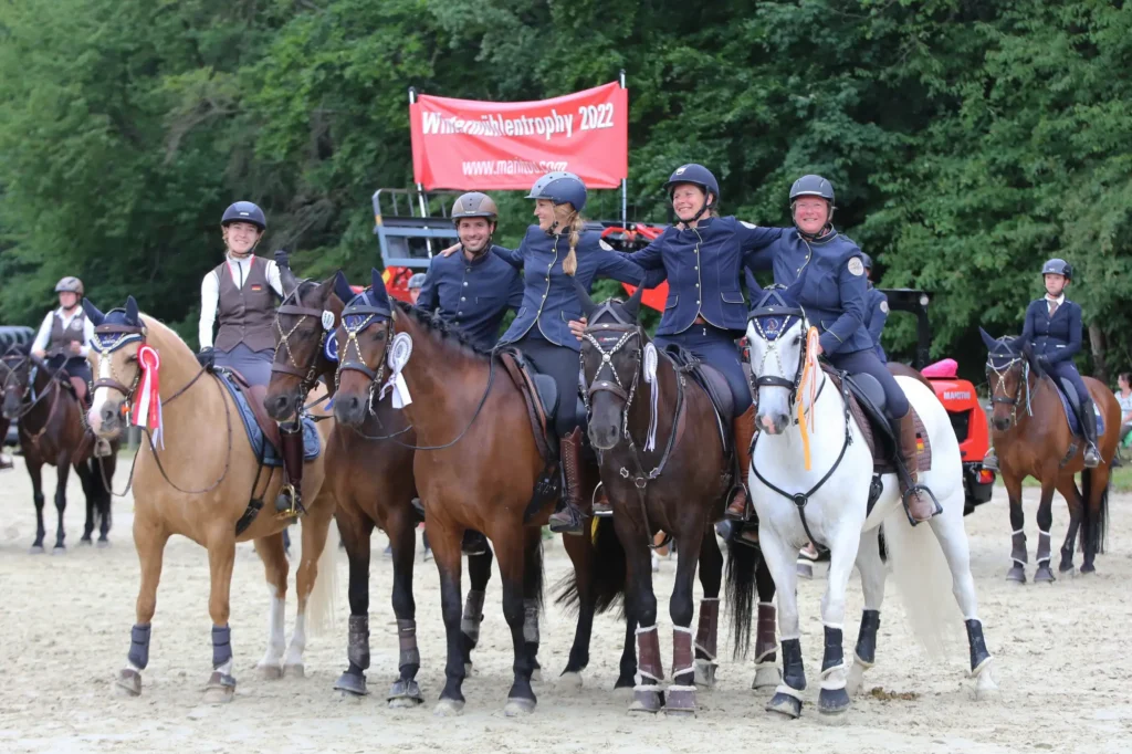 Reiter und Reiterinnen auf ihren Pferden umarmen sich bei der Siegerehrung - Working Equitation Deutschland